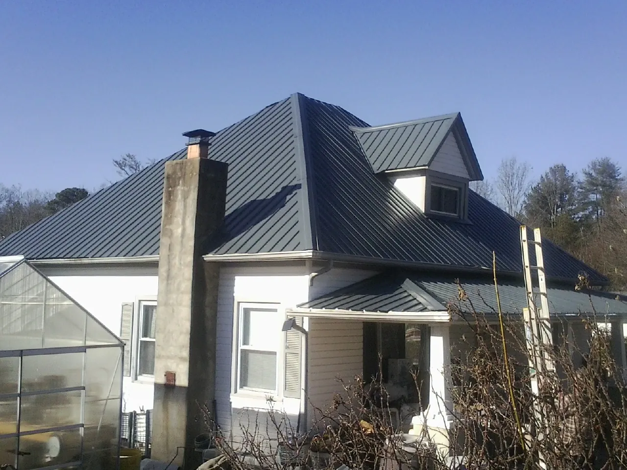 Dark blue standing seam metal roof on a white farmhouse with dormer — Slate & Tile Roof Repair by Roofing Brothers in Landis