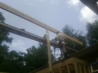 Carpenter setting a ridge beam over a new addition frame — Ice Dam Removal by Roofing Brothers in Landis