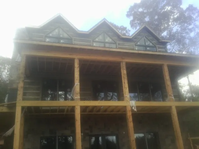 Dormers and porch framing on a large log home under construction — Roof Coating work by our crew in Landis