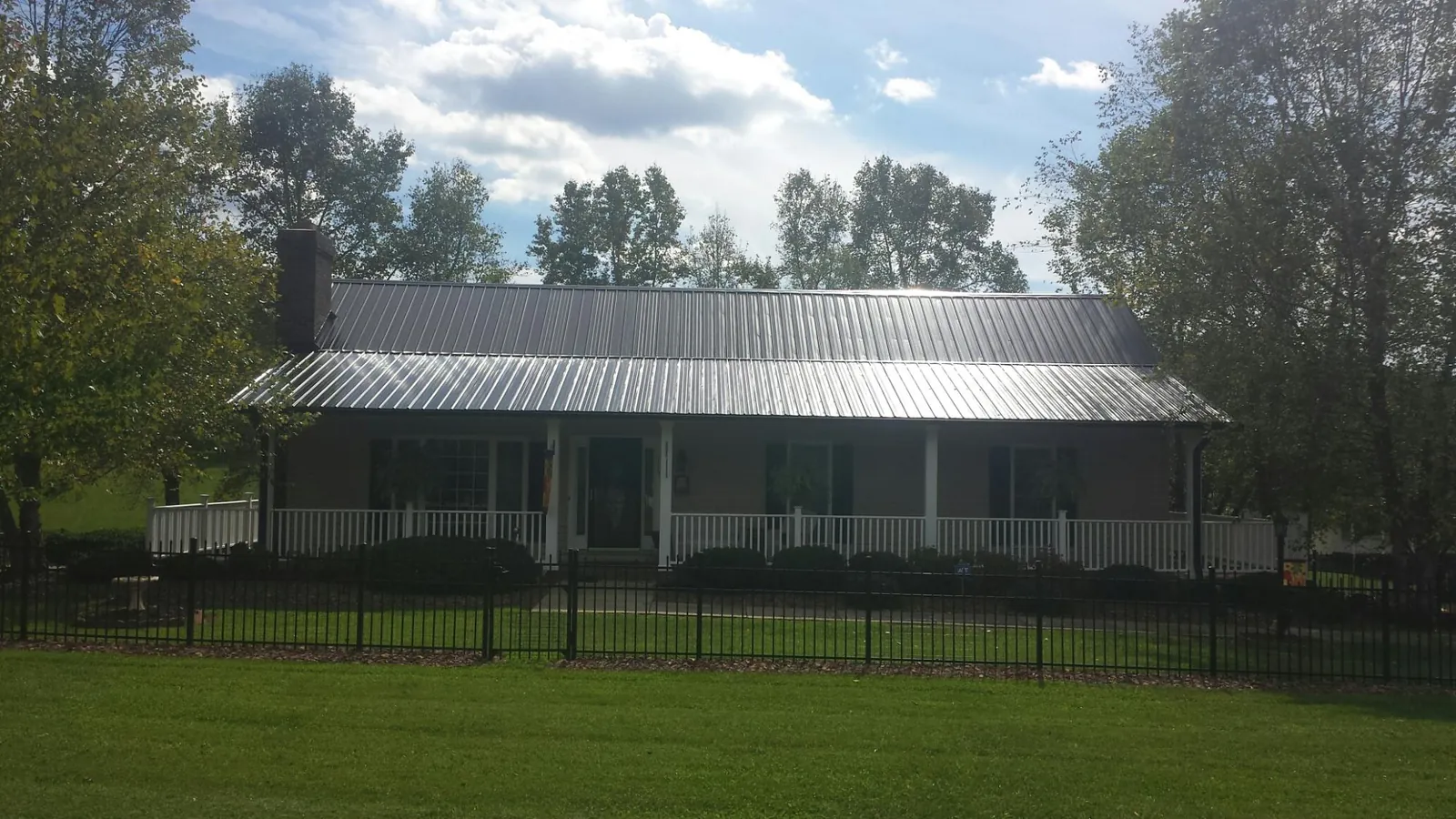Gray metal roof on a brick ranch with a full width front porch — Gutter Guard Installation work by our crew in Landis