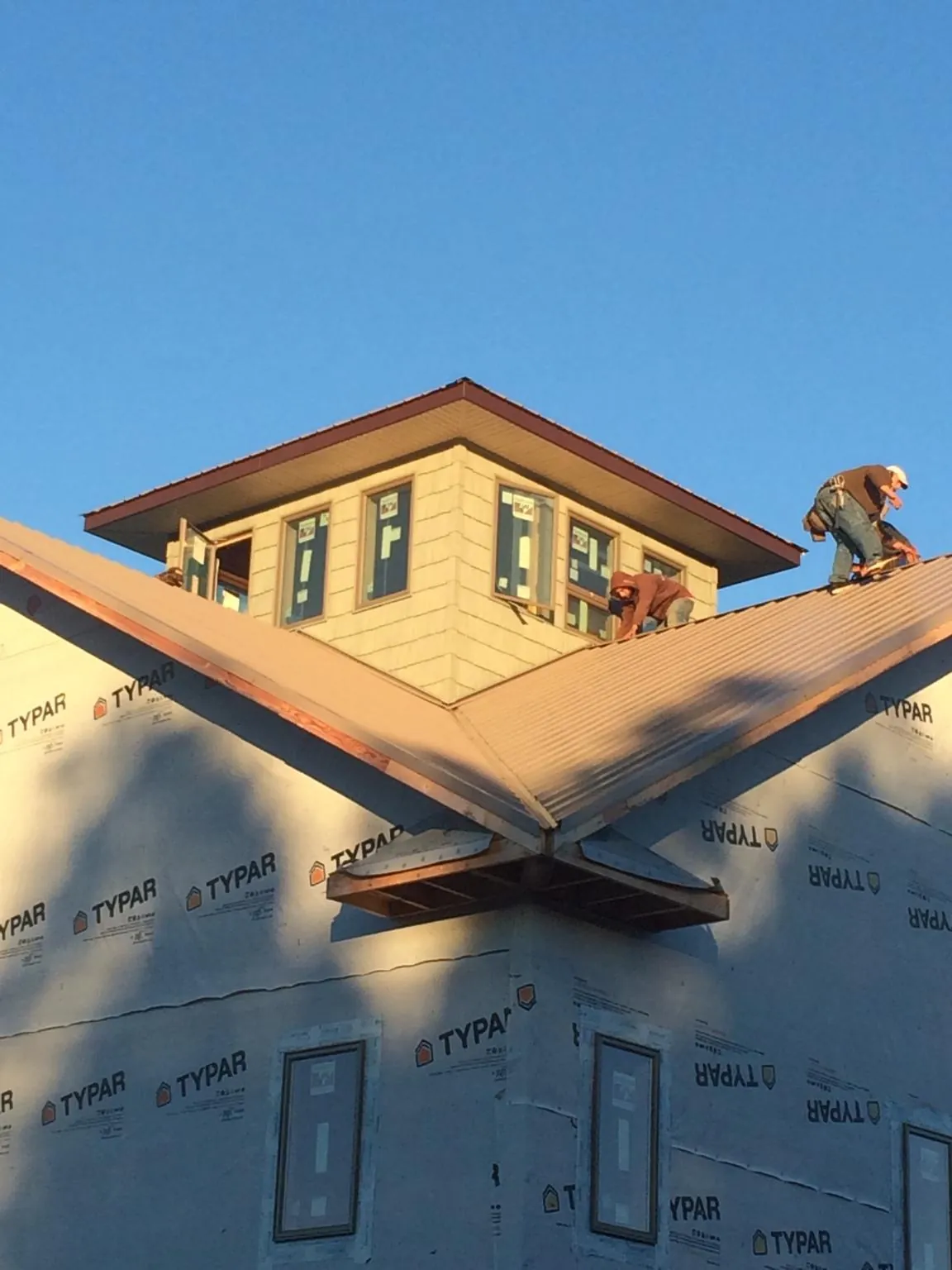 Roofers working around a rooftop cupola on a new metal roof at sunset — Roof Waterproofing in Landis by Roofing Brothers